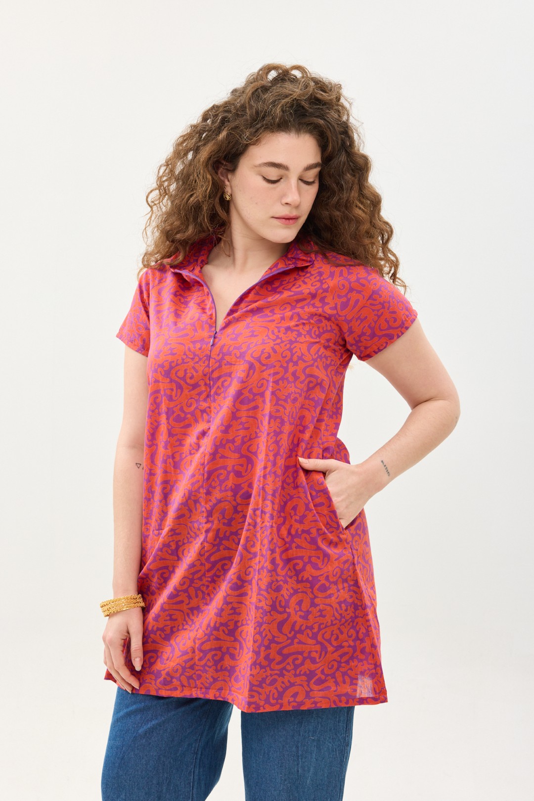 קומפורט זון: טוניקת מאיקו | טוניקה יפנית בעלת מפתח בעיצוב ייחודי. פרינט הפי פנטזי: דגם אוריינטלי ורוד כתום על רקע סגול. טוניקה באורך מחצית הירך, צווארון גבוה בשילוב רוכסן עמוק, עם שרוולים קצרים.