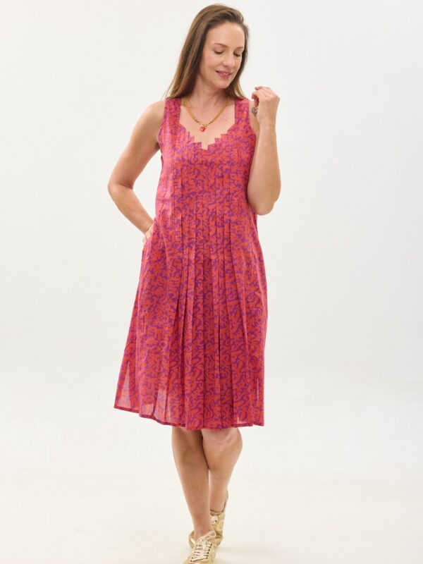 קומפורט זון: שמלת היידי | הפי פנטזי, פרינט של דגם אוריינטלי ורוד כתום על רקע סגול. שמלת גופיה באורך מתחת הברך, עם כתפיות רחבות, מפתח גאומטרי ואלמנט פליסה בחזית למראה מתוחכם