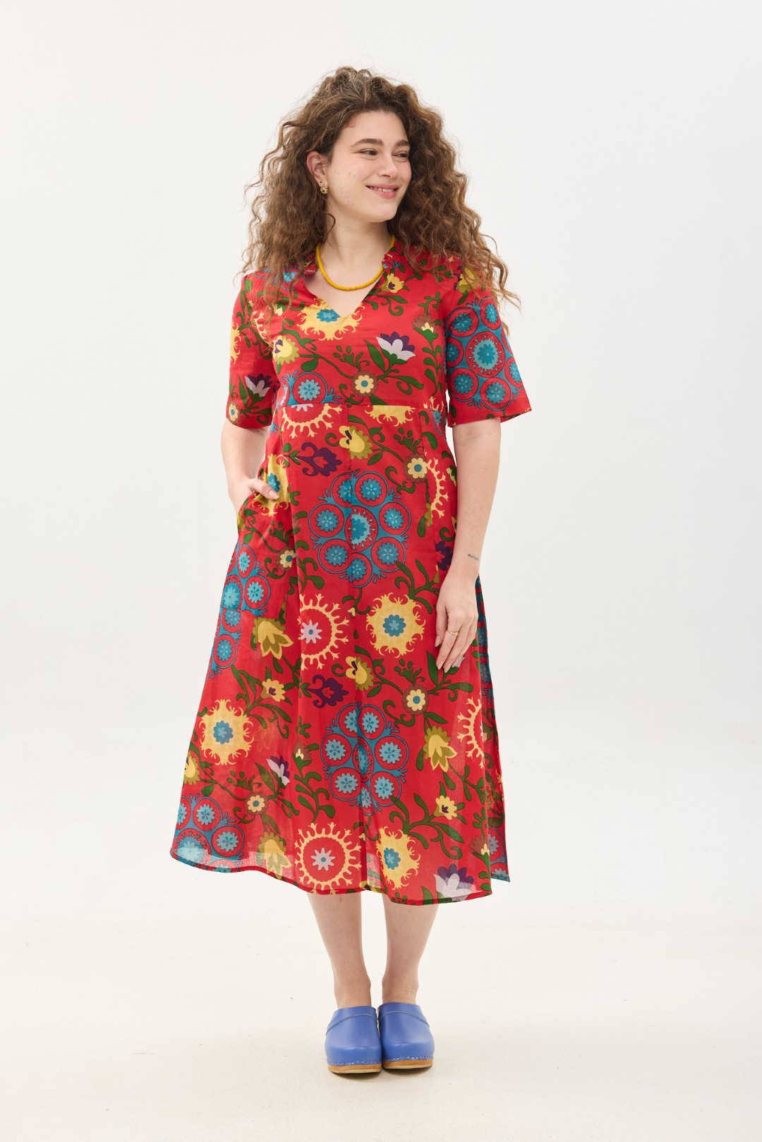 קומפורט זון: שמלת גילי | סוזני אדום. פרינט פלורילי בצהובים, ירוקים ותכולים על רקע אדום לוהב. שמלת אוברסייז מידי יפיפיה ונוחה עם צווארון וי, שרוולים עד המרפק, כיסים ותפר מדגיש מתחת לחזה.