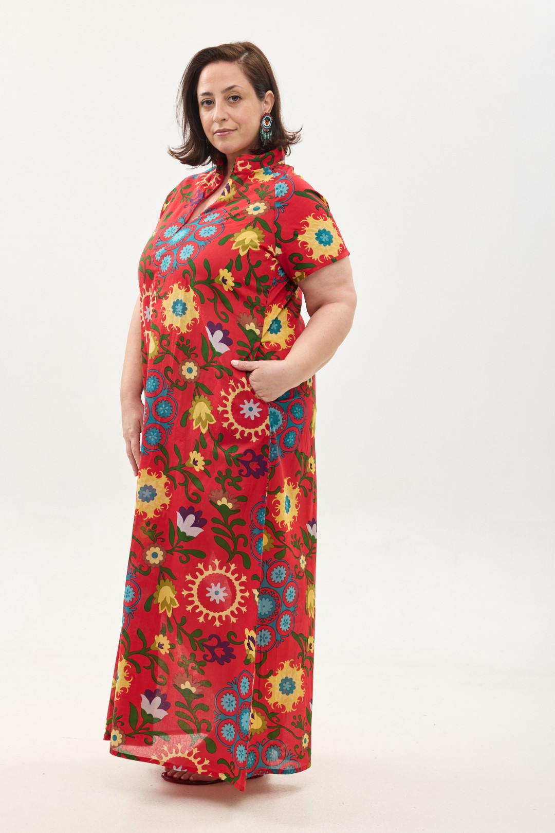 קומפורט זון: שמלת מאיקו, שרוול קצר | סוזני אדום. שמלת מקסי יפיפיה ונוחה, צווארון גבוה בשילוב רוכסן עמוק, עם שרוולים קצרים וכיסים. פרינט פלורילי בצהובים, ירוקים ותכולים על רקע אדום לוהב.