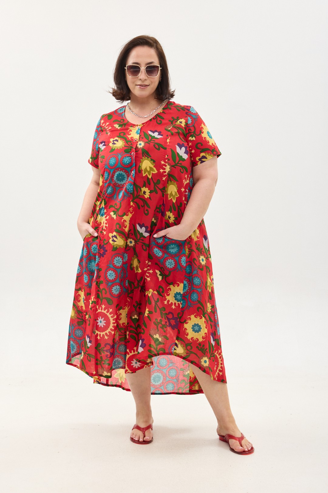 קומפורט זון: שמלת יפעת, שרוול קצר | סוזני אדום. פרינט פלורילי בצהובים, ירוקים ותכולים על רקע אדום לוהב. שמלת אוברסייז יפיפייה ונוחה, צווארון עגול, שרוולים קצרים, כפתורים מלמעלה עד למטה וכיסים קדמיים.