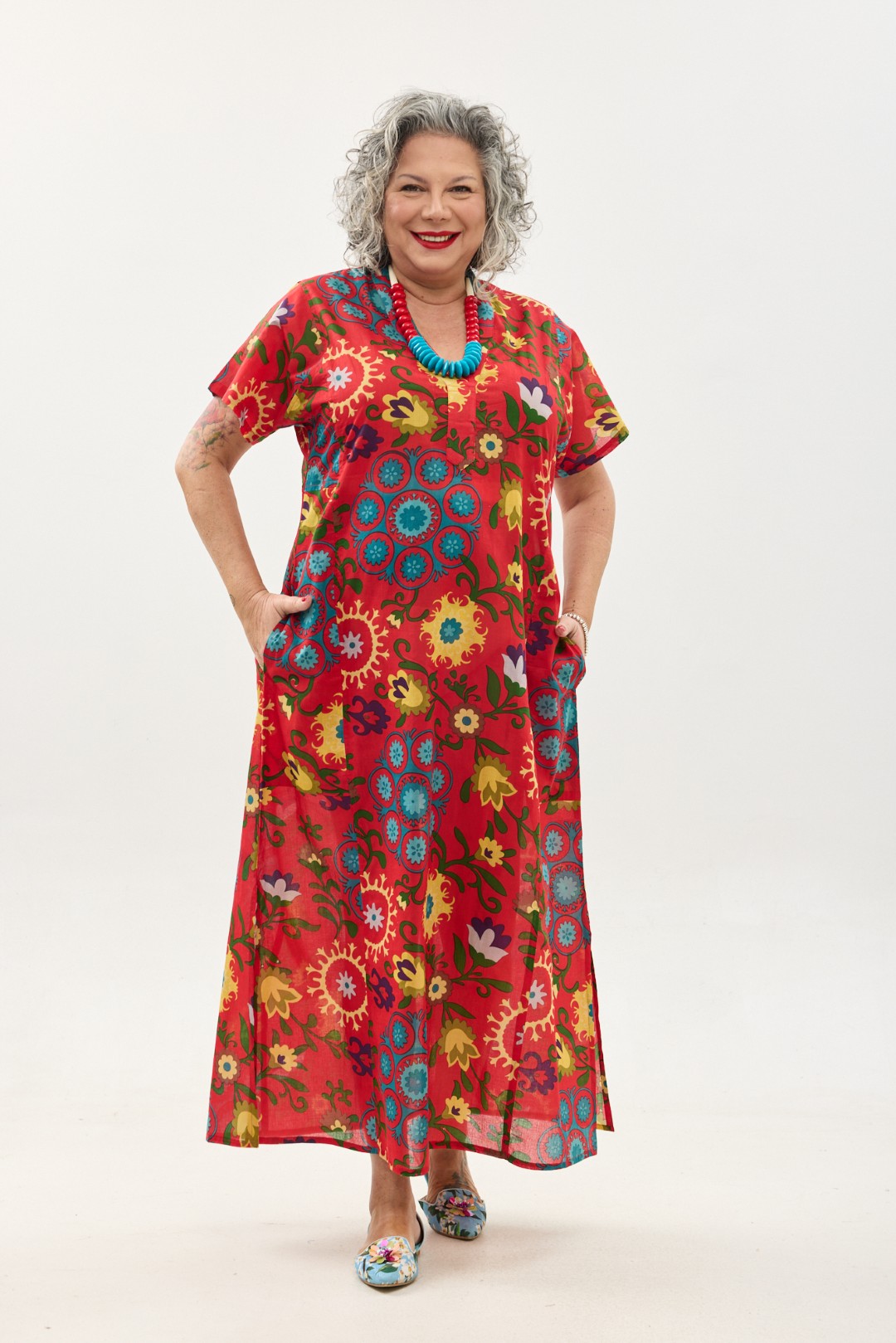 גלביה לנשים, שרוול קצר | סוזני אדום. גלבייה בעיצוב ייחודי – פרינט פלורילי בצהובים, ירוקים ותכולים על רקע אדום לוהב. שמלת גלביה נעימה ונוחה באורך הקרסול, צווארון ווי, שרוולים קצרים וכיסים צדדיים