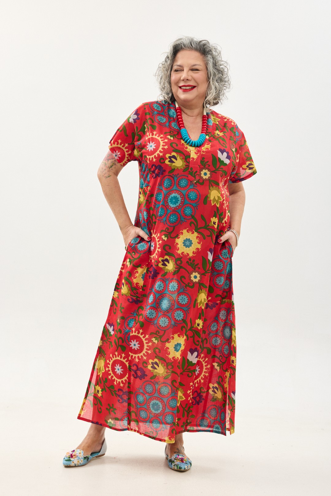 גלביה לנשים, שרוול קצר | סוזני אדום. גלבייה בעיצוב ייחודי – פרינט פלורילי בצהובים, ירוקים ותכולים על רקע אדום לוהב. שמלת גלביה נעימה ונוחה באורך הקרסול, צווארון ווי, שרוולים קצרים וכיסים צדדיים