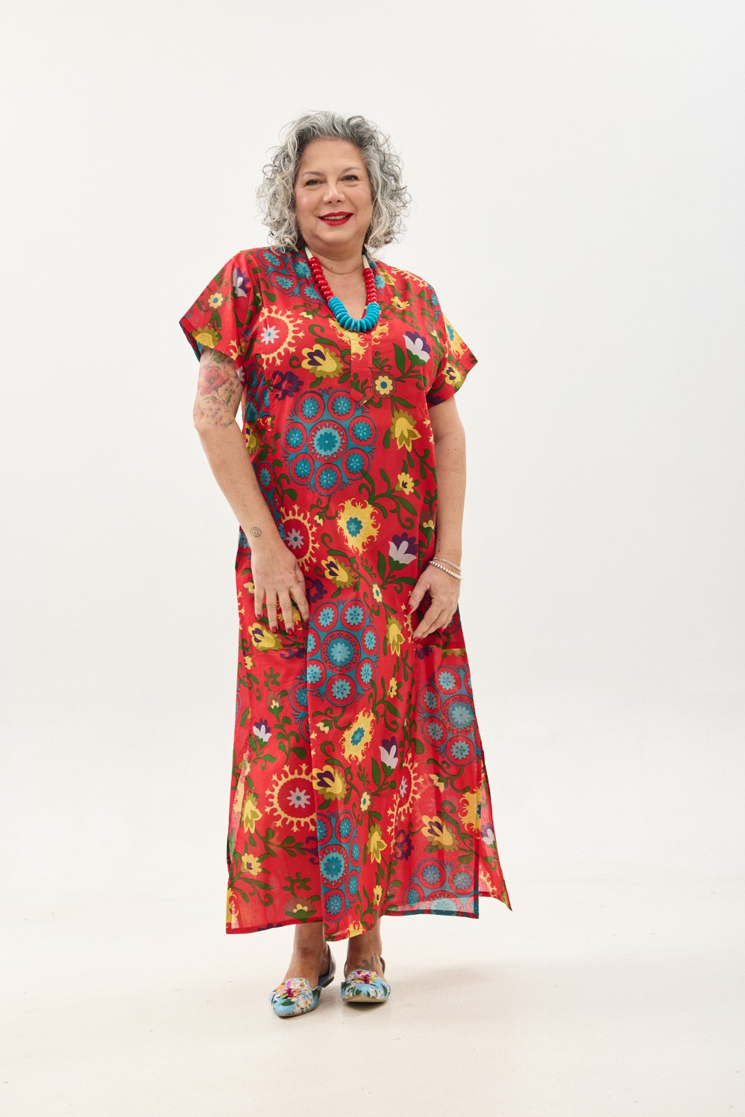 גלביה לנשים, שרוול קצר | סוזני אדום. גלבייה בעיצוב ייחודי – פרינט פלורילי בצהובים, ירוקים ותכולים על רקע אדום לוהב. שמלת גלביה נעימה ונוחה באורך הקרסול, צווארון ווי, שרוולים קצרים וכיסים צדדיים