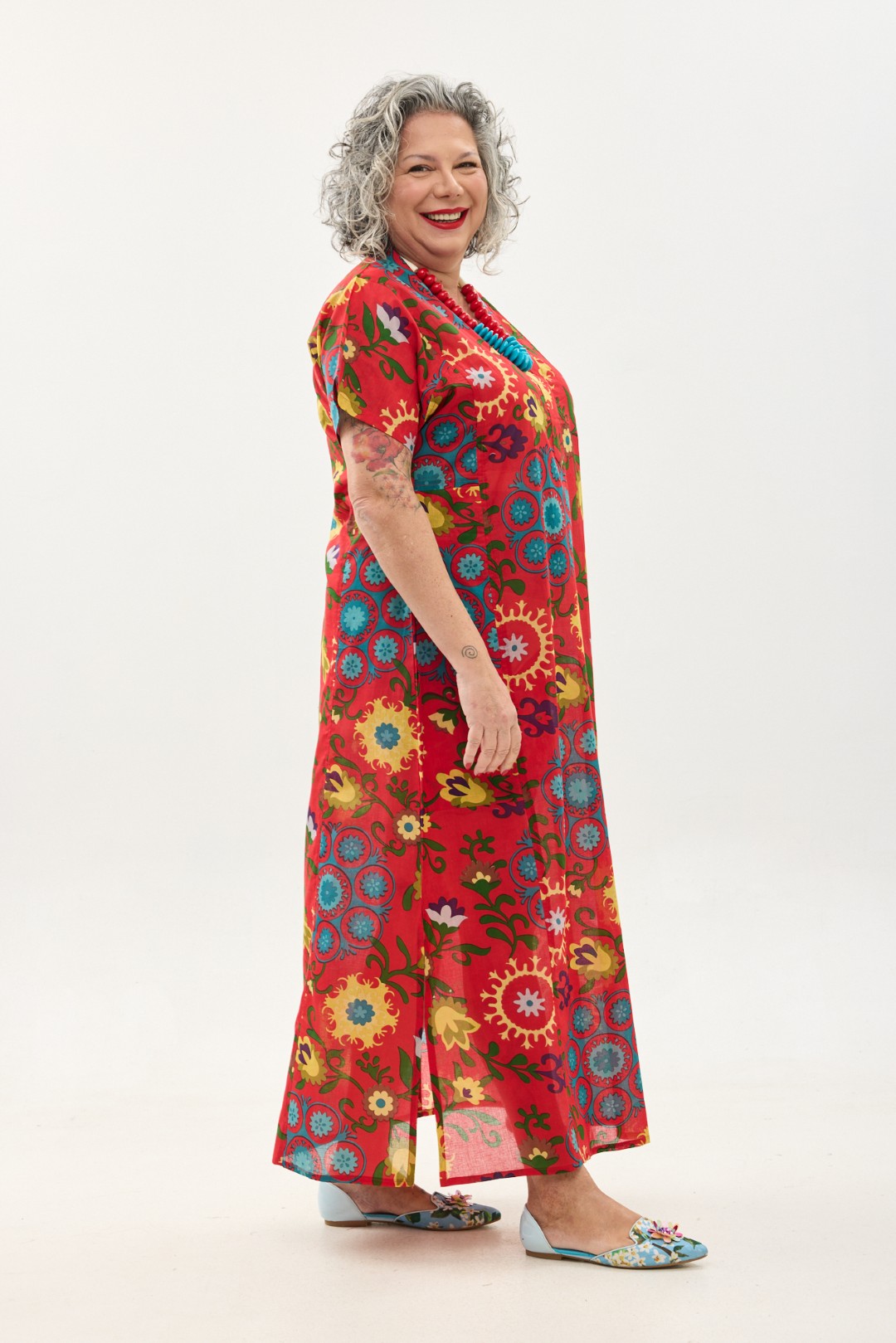 גלביה לנשים, שרוול קצר | סוזני אדום. גלבייה בעיצוב ייחודי – פרינט פלורילי בצהובים, ירוקים ותכולים על רקע אדום לוהב. שמלת גלביה נעימה ונוחה באורך הקרסול, צווארון ווי, שרוולים קצרים וכיסים צדדיים